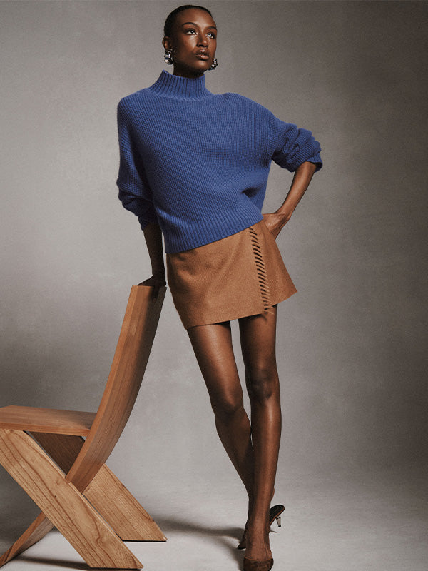 Model wears a White + Warren’s Cashmere Waffle Standneck sweater with a tan mini skirt.
